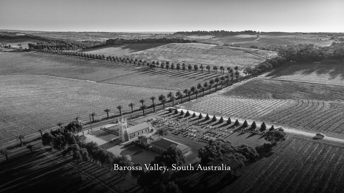 Black and white aerial photograph of Barossa Valley, South Australia, showing rolling vineyard fields, tree-lined roads, and Marananga Church near the center with the text 'Barossa Valley, South Australia' at the bottom left.